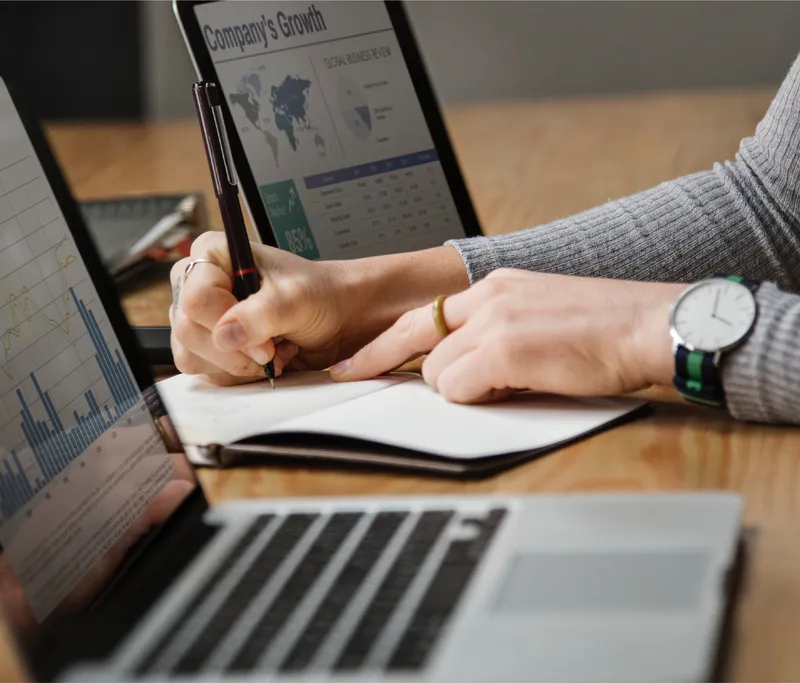 Taking notes on a growth plan beside a laptop
